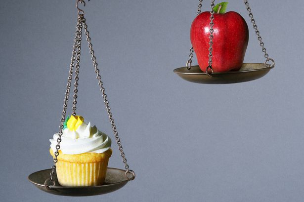 Scale weighing the value of a cupcake and apple